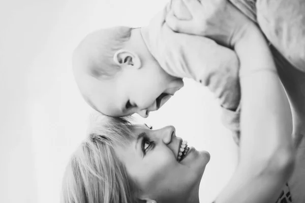 Mother holding her baby up and toching by noses. — Stock Photo, Image