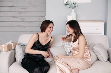 İki genç kız kardeş evde kanepede oturup konuşuyor