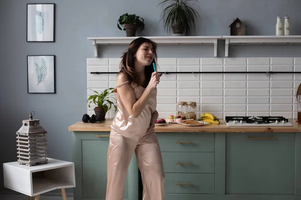 Молода дівчина в піжамі танцює вранці на кухні — стокове фото