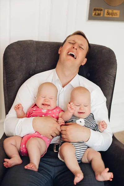 Utmattad pappa hålla två små tvillingar och gråta — Stockfoto