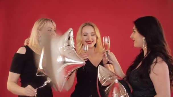Mulheres positivas felizes com copos de champanhe dançando no fundo vermelho . — Vídeo de Stock