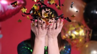 Mutlu kadın kameraya pırıl pırıl konfeti üfleme