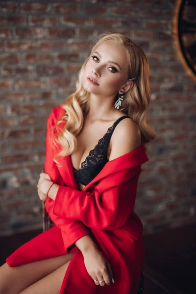 Prachtige blonde vrouw in rode jurk kijken naar camera. — Stockfoto