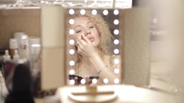 Loira olhando para o espelho e fazendo maquiagem em casa — Vídeo de Stock