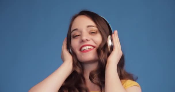 Радостная молодая женщина танцует, слушая музыку в наушниках . — стоковое видео