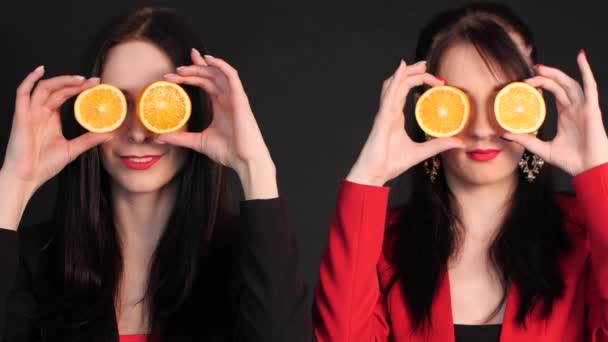 Mujeres sosteniendo naranjas a la mitad delante de sus ojos . — Vídeos de Stock