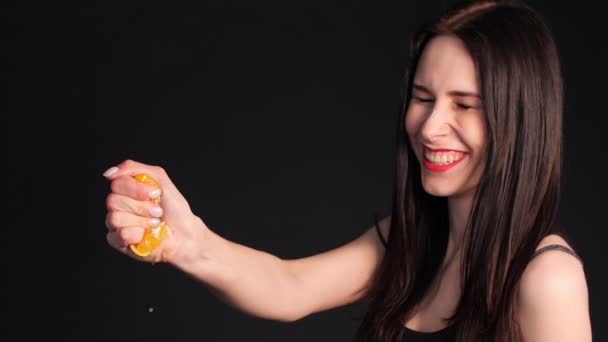 Божевільна молода брюнетка стискає апельсин в руці — стокове відео