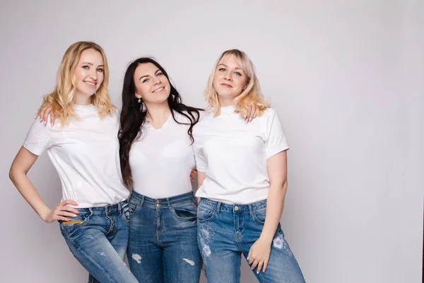Trzy piękne kobiety w białych koszule i dżinsy stwarzające — Zdjęcie stockowe