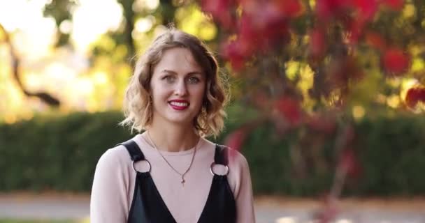 Superbe jeune femme aux cheveux blonds mi-longs et aux lèvres rouges dans le parc d'automne . — Video