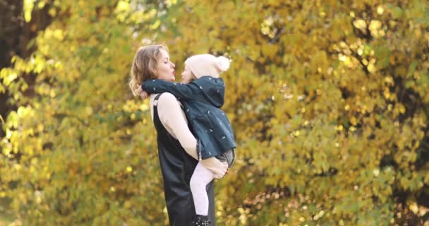 Mutter hält ihre Tochter auf dem Arm und küsst sie im Garten. — Stockvideo