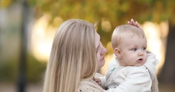 Liefdevolle moeder met een baby in Spring Park. — Stockvideo