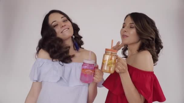 Dos hermanas jóvenes bebiendo zumo de naranja fresco — Vídeos de Stock