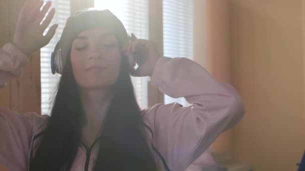 Dos hermanas activas en sombreros y auriculares escuchando música — Vídeos de Stock