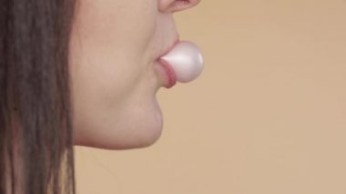 Pembe sakız üfleme genç kadının yan görünümü