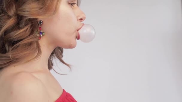 Side view of young woman blowing pink bubble gum — Stock Video