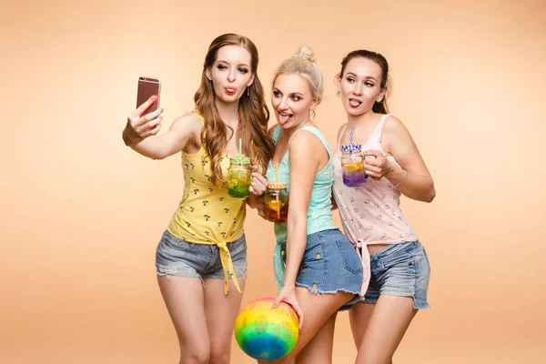 Gorgeous slim friends with fresh summer drinks taking selfie via mobile. — Stock Photo, Image