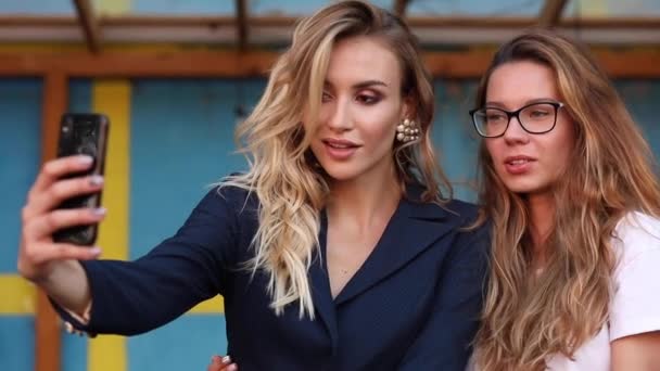 İki çekici kadın telefonda selfie çekip poz verirken — Stok video