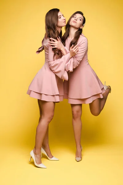 Sorelle felici in abiti rosa sorridenti e in piedi insieme . — Foto Stock