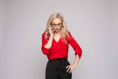 Kırmızı bluzlu ve etekli kadın telefonunu tutuyor ve gülüyor.