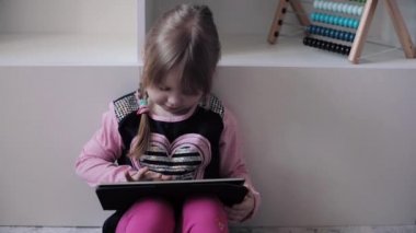 Katta oturan ve elektronik aygıtlar kullanarak komik çocuk.