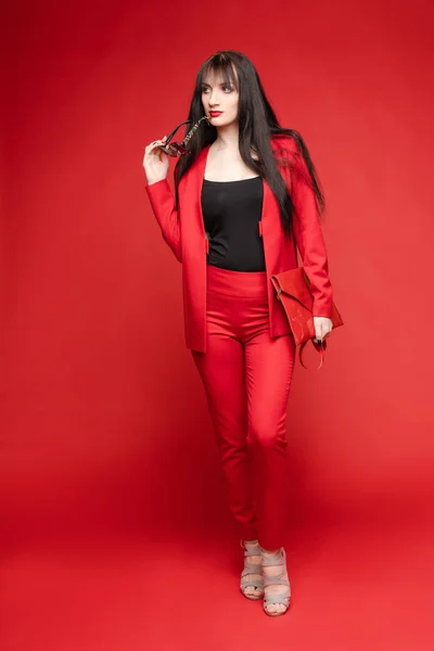 Zijaanzicht van glamoureuze brunette poseren in rood slim pak — Stockfoto