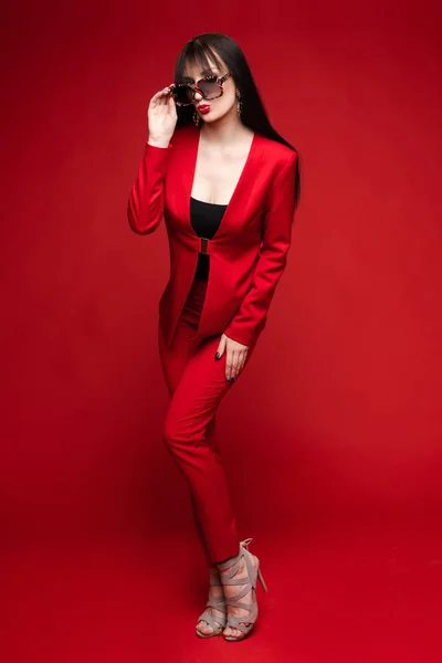 Πλευρική όψη του λαμπερή μελαχρινή που ποζάρει με κόκκινο έξυπνο κοστούμι — Φωτογραφία Αρχείου