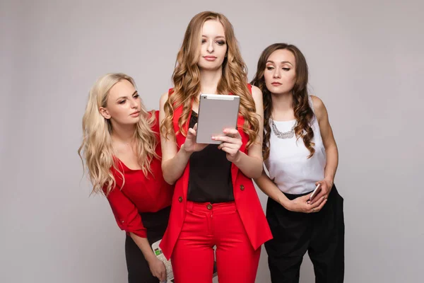 Three ladies using gadgets. Three gorgeous elegant young women in casual clothe — Stock Photo, Image