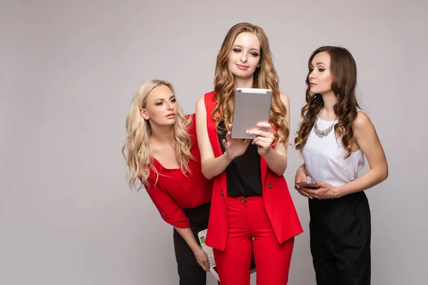 Stylish elegant woman in red suit using tablet with friends. — Stock Photo, Image