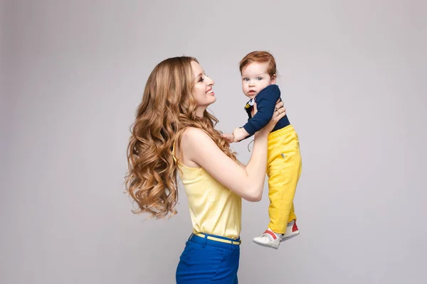 Mujer joven y en forma en ropa casual sosteniendo niño pequeño . — Foto de Stock