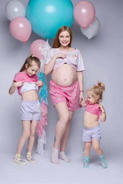 Fotografie amuzantă a unei mame însărcinate superbe cu două fiice care se uită la burtă . — Fotografie, imagine de stoc