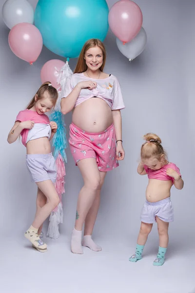 Photo drôle de magnifique mère enceinte avec deux filles regardant leurs ventres . — Photo