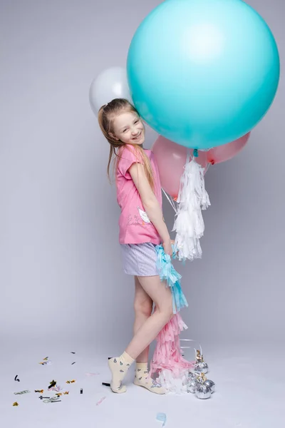 Süßes kleines Mädchen mit roten Haaren und Sommersprossen im Pyjama mit Luftballons. — Stockfoto