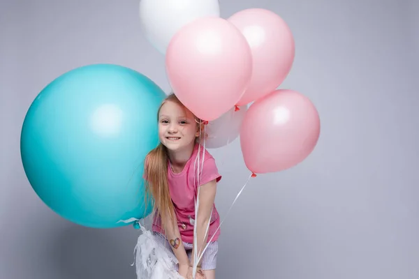 Süßes kleines Mädchen mit roten Haaren und Sommersprossen im Pyjama mit Luftballons. — Stockfoto