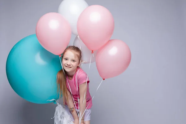 Süßes kleines Mädchen mit roten Haaren und Sommersprossen im Pyjama mit Luftballons. — Stockfoto