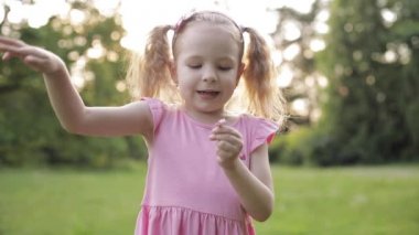 Midilli kuyrukları ile sevimli küçük kız çayır üzerinde çiçek yaprakları toplama.