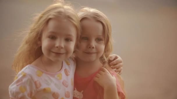 Entzückende kleine Mädchen, die sich im Sonnenlicht umarmen. — Stockvideo