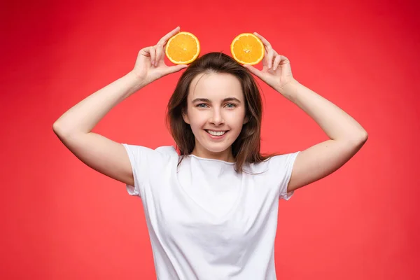 Смішна модна дівчина з зачіскою, що тримає апельсини на очах . — стокове фото