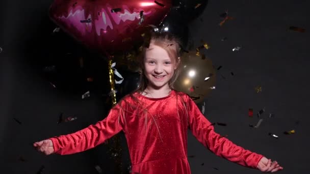 Lovely happy little girl jumping with confetti and air balloons in background. — Stock Video