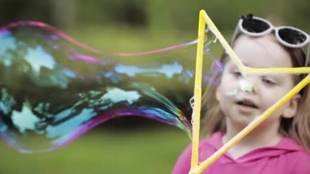 Söt liten unge blåser en bubbla i parken. — Stockvideo