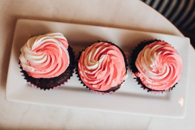 Beyaz seramik tabakta servis edilen lezzetli çilekli cupcake'ler.