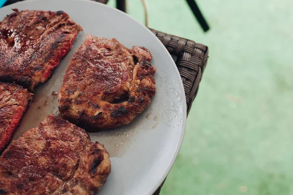 Appetitlich gegrilltes frisches Steak medium gebraten auf weißem Teller umgeben von grünem Gras — Stockfoto