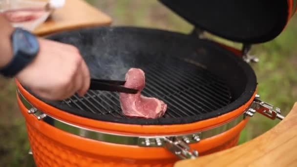Nahaufnahme männliche Hand hält Pinzette Drehen rohes frisches Fleisch Stück machen Grill — Stockvideo