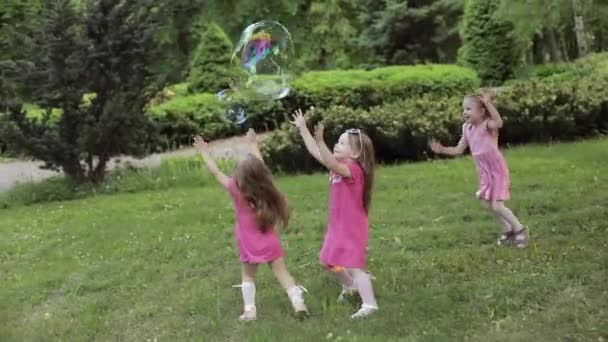Lyckliga små flickor som leker i trädgården och leker bubblor — Stockvideo