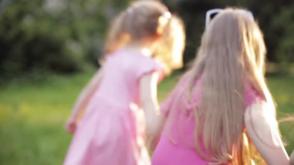 Trois petite fille tenant par les mains courant sur l'herbe verte au jardin entouré par le ventilateur à bulles d'air 