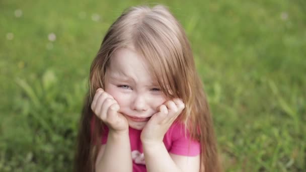 Αναστατωμένος όμορφο μικρό χαριτωμένο κορίτσι κλάμα στο λιβάδι που περιβάλλεται από πράσινο γρασίδι μεσαία κοντά — Αρχείο Βίντεο