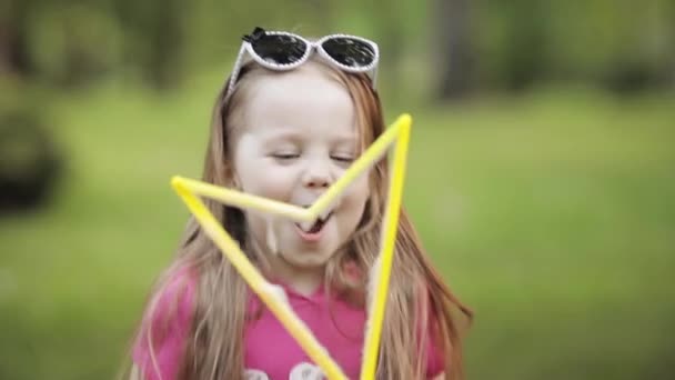 Впевнена грайлива маленька мила дівчинка дме величезне повітряне мило бульбашкове вентилятор середовище крупним планом — стокове відео