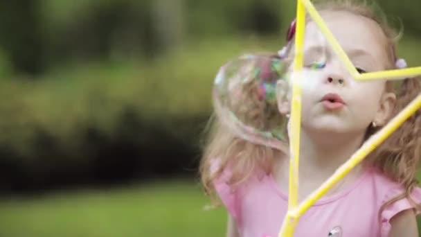 Söt liten unge blåser en bubbla i parken. — Stockvideo