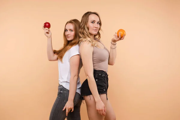 Dos chicas deportivas posando con verduras y frutas útiles — Foto de Stock
