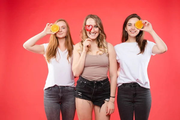 Três meninas felizes com laranjas e doces doces . — Fotografia de Stock