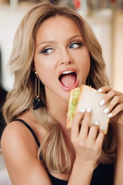 Atrakcyjna kobieta jedząca pyszne kanapkę w kawiarni — Zdjęcie stockowe